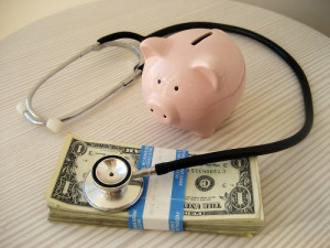 a piggy bank, stack of cash, and a stethoscope